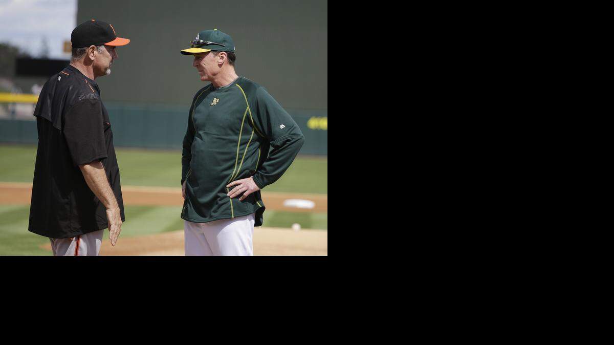 Giants manager Bruce Bochy, left, talks with A’s manager Bob Melvin before the start of the teams’ spring training game Tuesday.