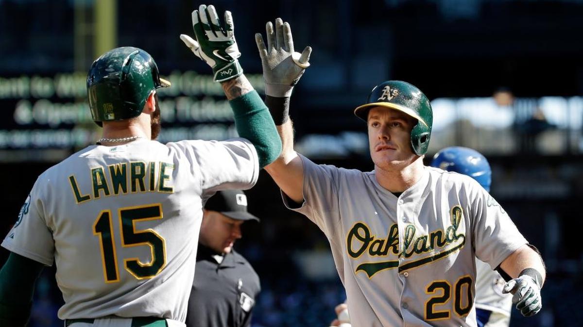 A’s infielder Mark Canha (20) is congratulated by Brett Lawrie after scoring on Oct. 4, 2015, in Seattle.
