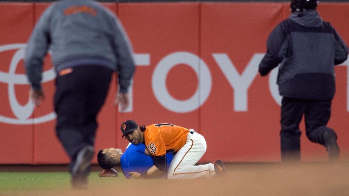 San Francisco Giants’ Angel Pagan (16) holds down a man who ran onto the field during the fourth inning of the Giants' baseball game against the Los Angeles Dodgers, Friday, Sept. 30, 2016, in San Francisco.