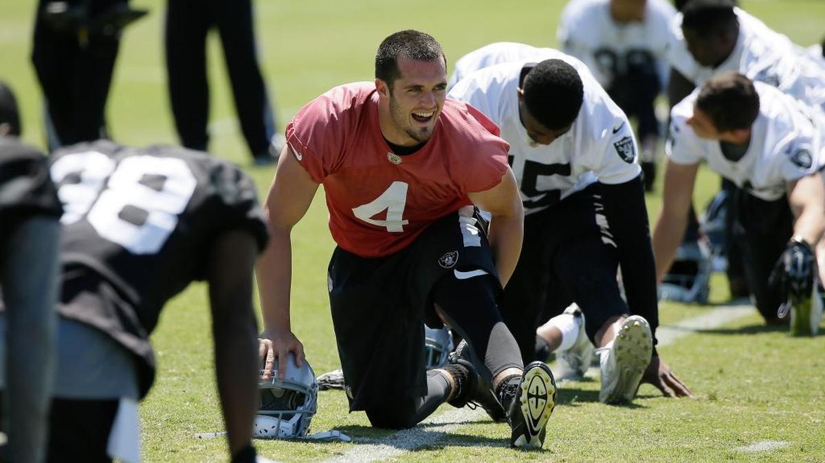 Oakland Raiders quarterback Derek Carr laughs while stretching during the team’s NFL football minicamp Wednesday, June 15, 2016, in Alameda, Calif.