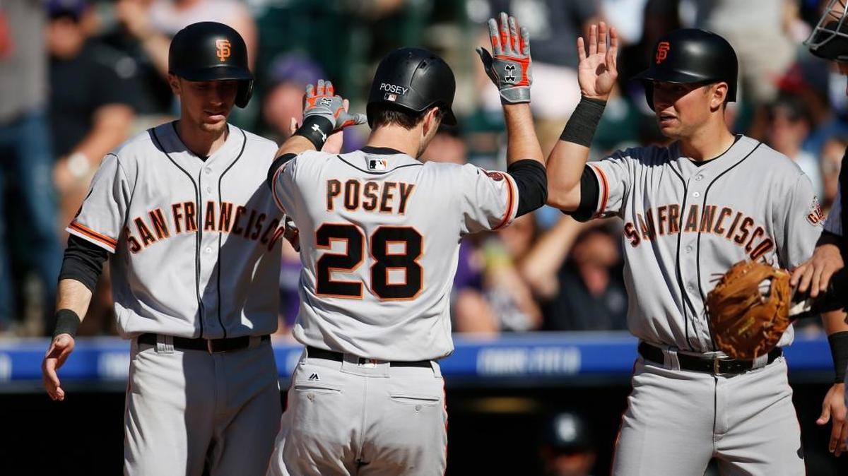 San Francisco Giants catcher Buster Posey, center, is congratulated by teammates Matt Duffy, left, and Joe Panik while after hitting a three-run homer off Colorado Rockies reliever Carlos Estevez in the eighth inning of a baseball game Saturday, May 28, 2016, in Denver.