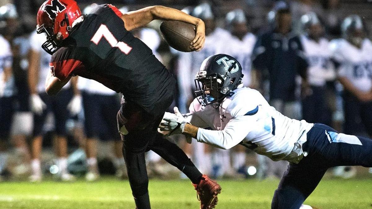 Modesto quarterback R.J. Berumen slips away from a Downey defender during the Modesto Metro Conference League game in Modesto, Calif., on Friday, October 21, 2016.