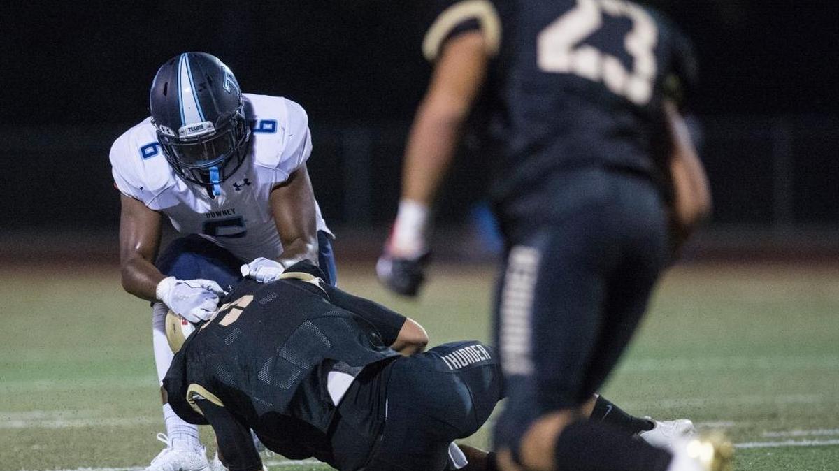 Downey senior Xavier Lewis (6) tackles Buhach Colony senior quarterback Clay Abrams (5) during a non-conference game at Atwater High School in Atwater, Calif., on Friday, Aug. 25, 2017.
