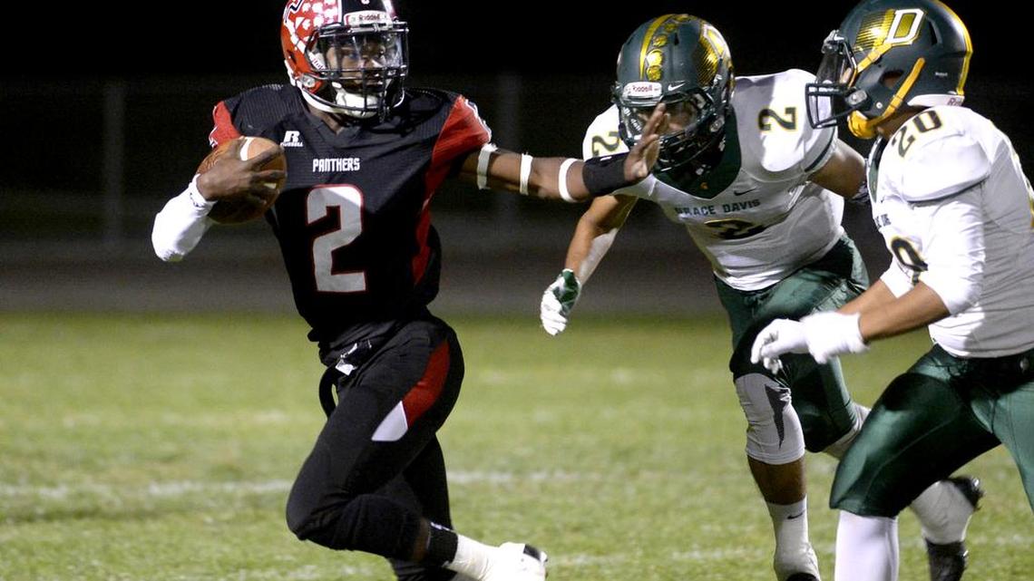 Modesto's Norvale Howard (2), left, strikes a Heisman Trophy pose to fend off Davis tacklers, during the Modesto High homecoming football game against Davis High, at Gregori's Don Lanphear Stadium, Friday, September 29, 2017 in Salida, Calif.