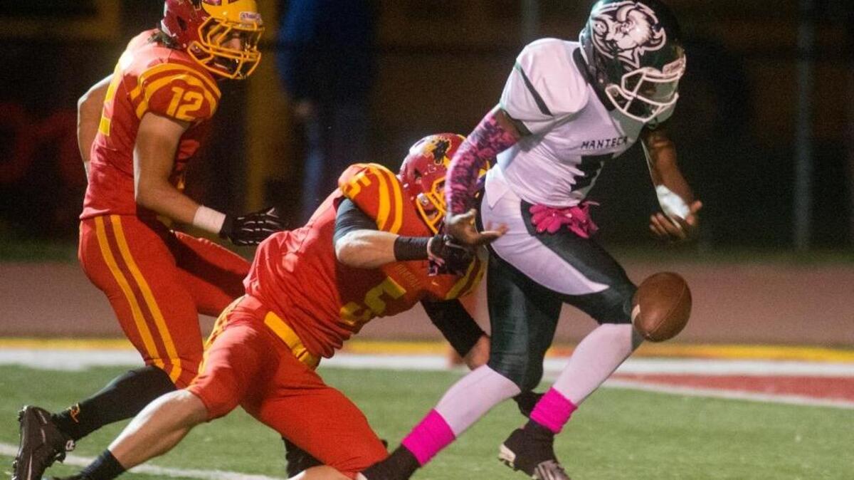 Oakdale linebacker Lane Trapp (5) forces Manteca’s Dakarai Charles (8) to fumble during a game between Oakdale High School and Manteca High School in Oakdale on Friday.