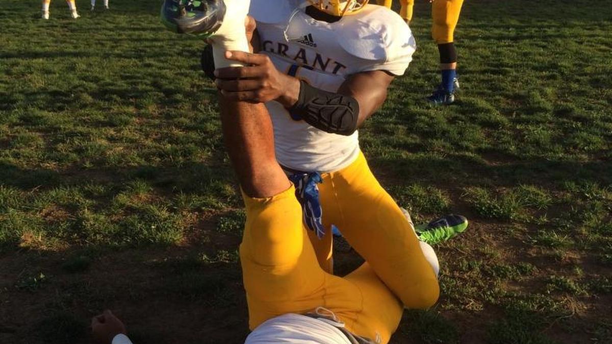 Jaulon Clavo, kneeling, helps teammate, David Moala stretch during warmups at Grant High versus Franklin High School game at Consumnes Oaks on September 25, 2015. Clavo was shot and killed on November 13, 2015.