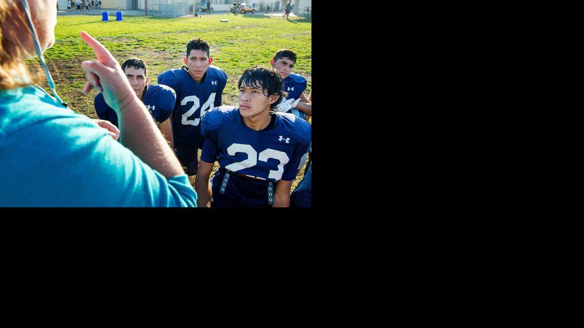 
Interpreter Cathy Johnson signs for deaf Downey players Jed McGuire (23), Omar Ruiz (24) and Alejandro Lobato (1) during a post practice huddle.

