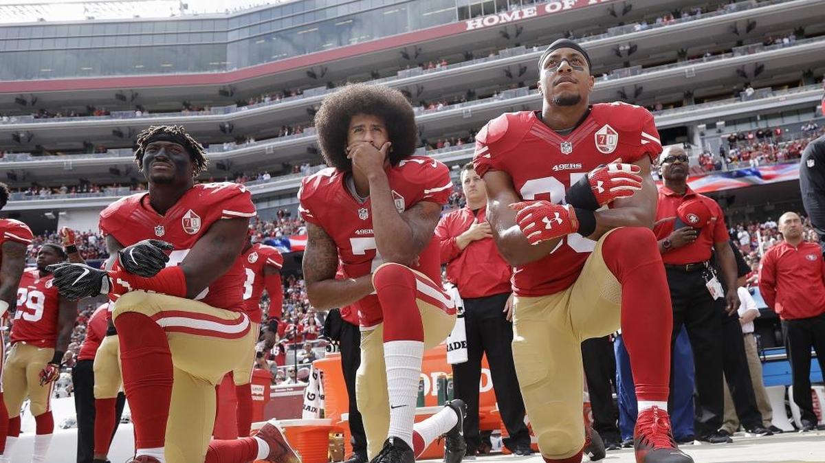 In this Oct. 2, 2016, file photo, from left, San Francisco 49ers outside linebacker Eli Harold, quarterback Colin Kaepernick and safety Eric Reid kneel in protest during the national anthem before an NFL football game against the Dallas Cowboys in Santa Clara, Calif.