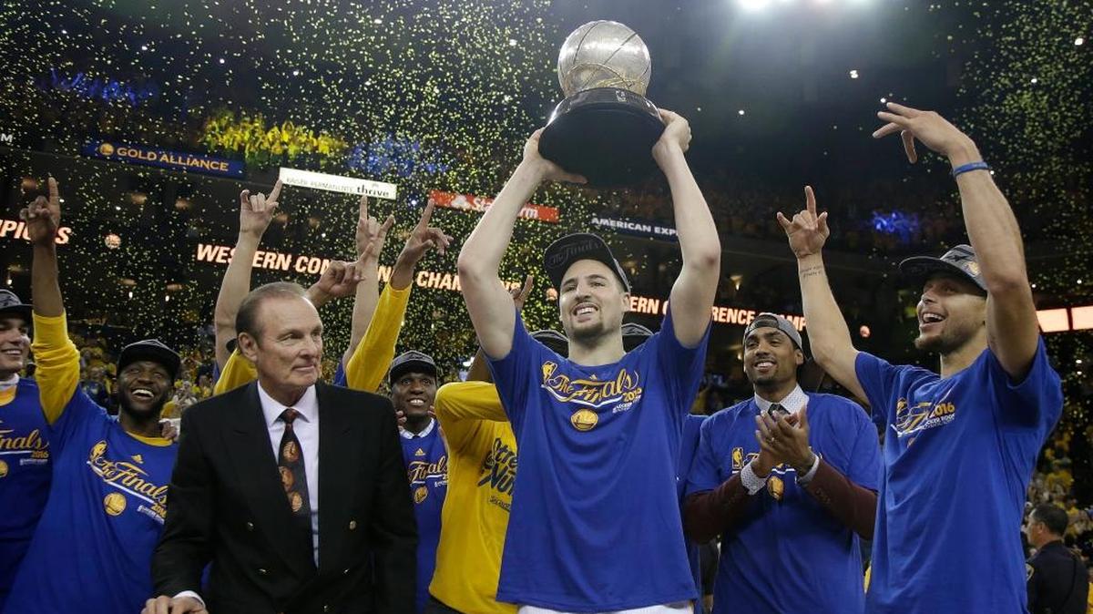 Former NBA player Rick Barry, center left, watches as Golden State Warriors guard Klay Thompson, center, Stephen Curry, right, and their teammates celebrate after beating the Oklahoma City Thunder in Game 7 of the NBA basketball Western Conference finals, Monday, May 30, 2016 in Oakland. The Warriors won 96-88.