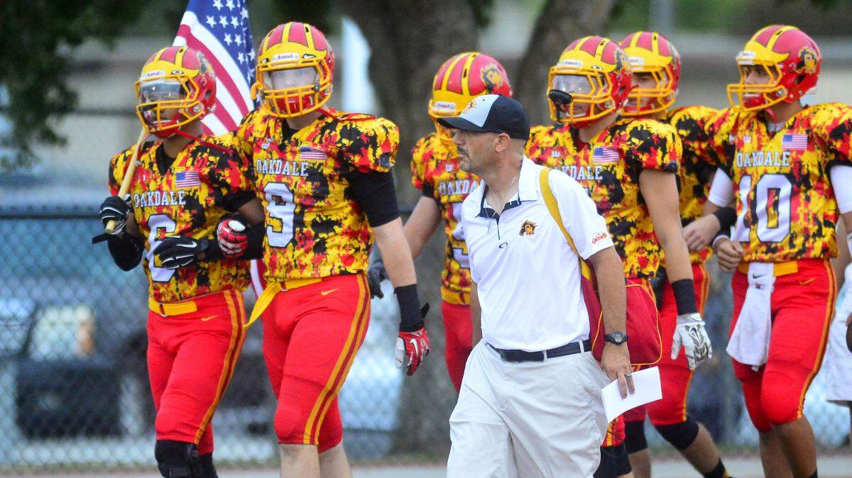 Oakdale head coach Trent Merzon walks out with his team before a game between Oakdale and Menlo-Atherton at Oakdale High in 2015.