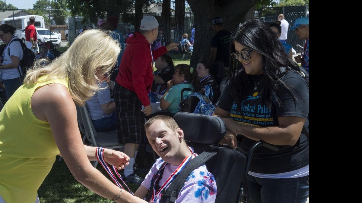 Raymond Vauhn, center, receives a medal Friday from three-time Olympian Suzy Powell, left, during the Olympic Day, a Special Olympics event sponsored by United Cerebral Palsy, at the SOS club in Modesto.