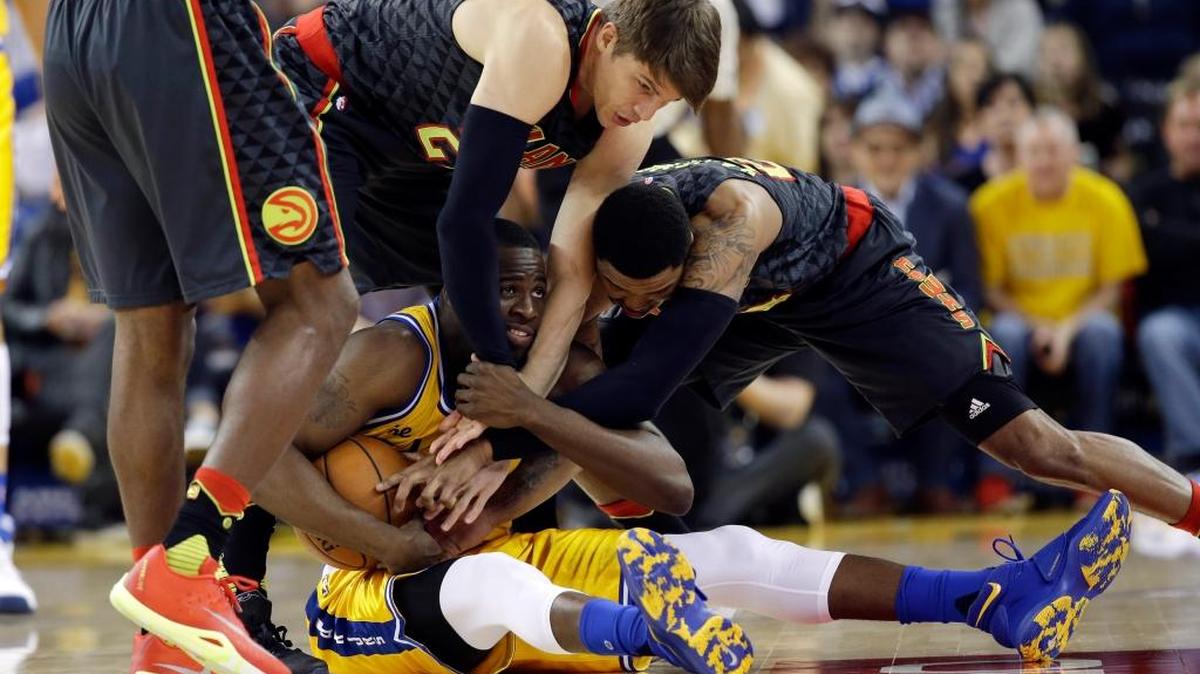 The Golden State Warriors’ Draymond Green, center, fights for a loose ball against Atlanta Hawks’ Kyle Korver, left, and Kent Bazemore, right, during an NBA basketball game, Tuesday, March 1, 2016, in Oakland.